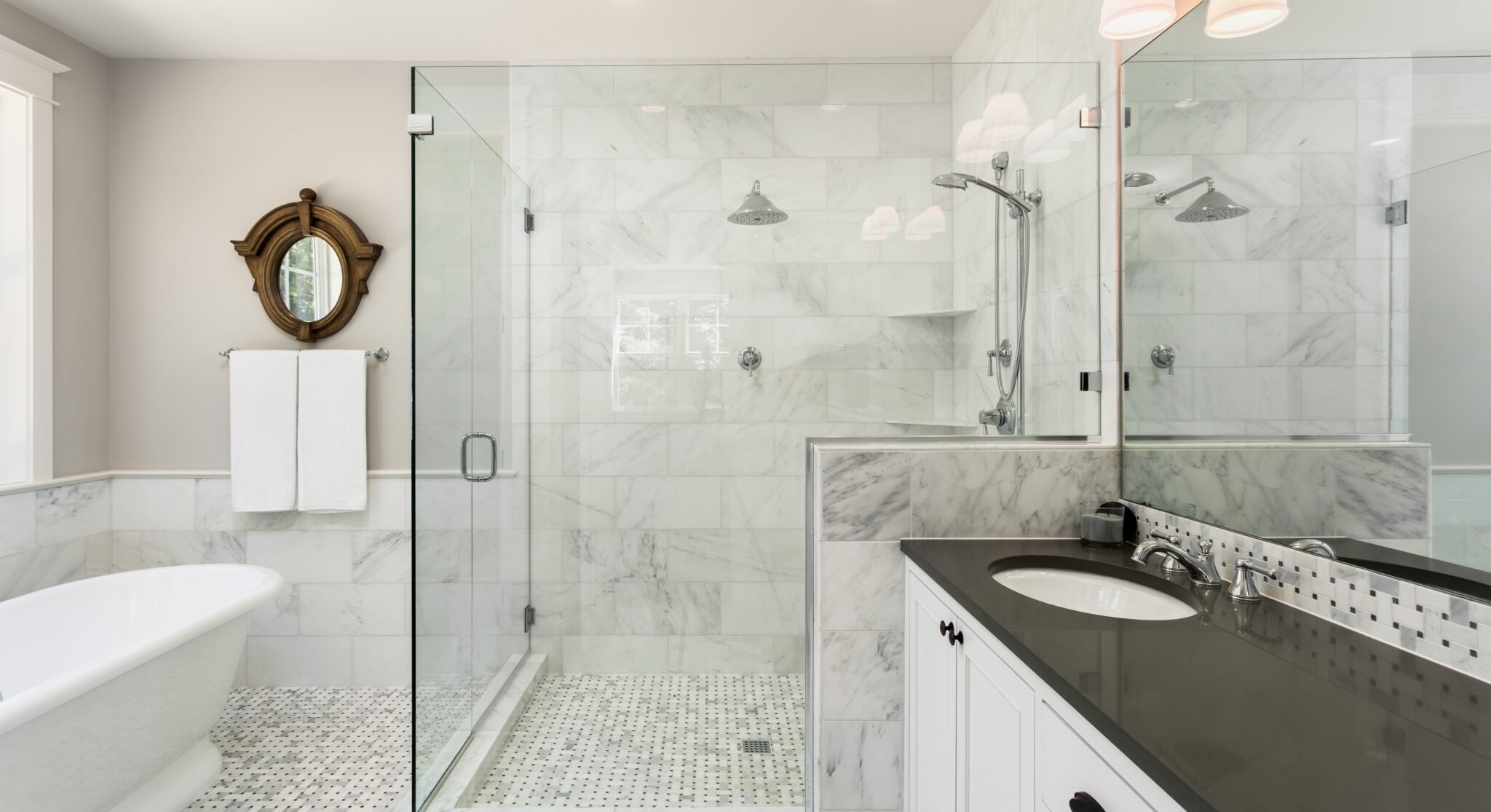 A tiled and marble bathroom with a glass frameless shower screen by Artform Collective.
