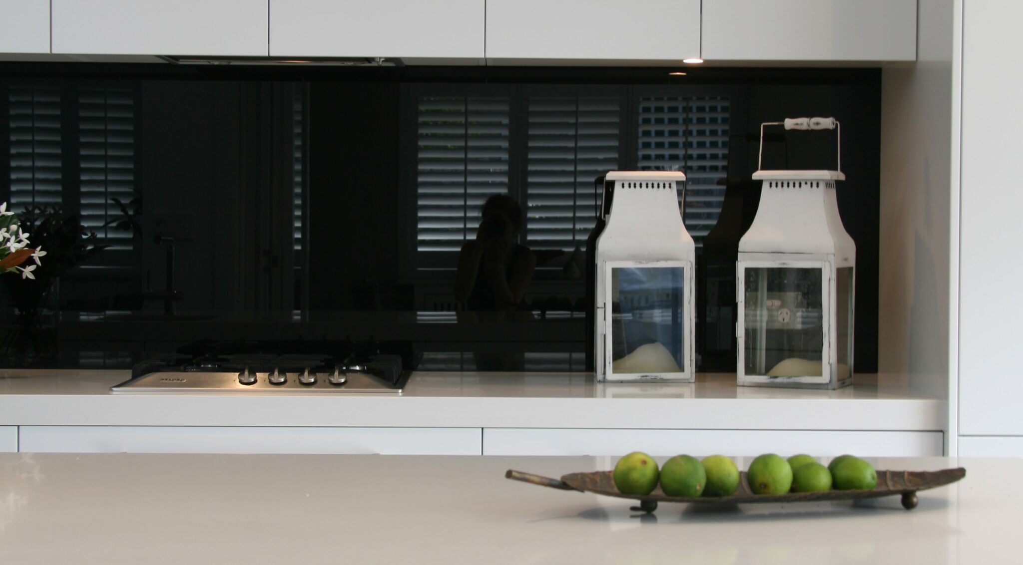 An island kitchen featuring a black glass splashback by Artform Collective.